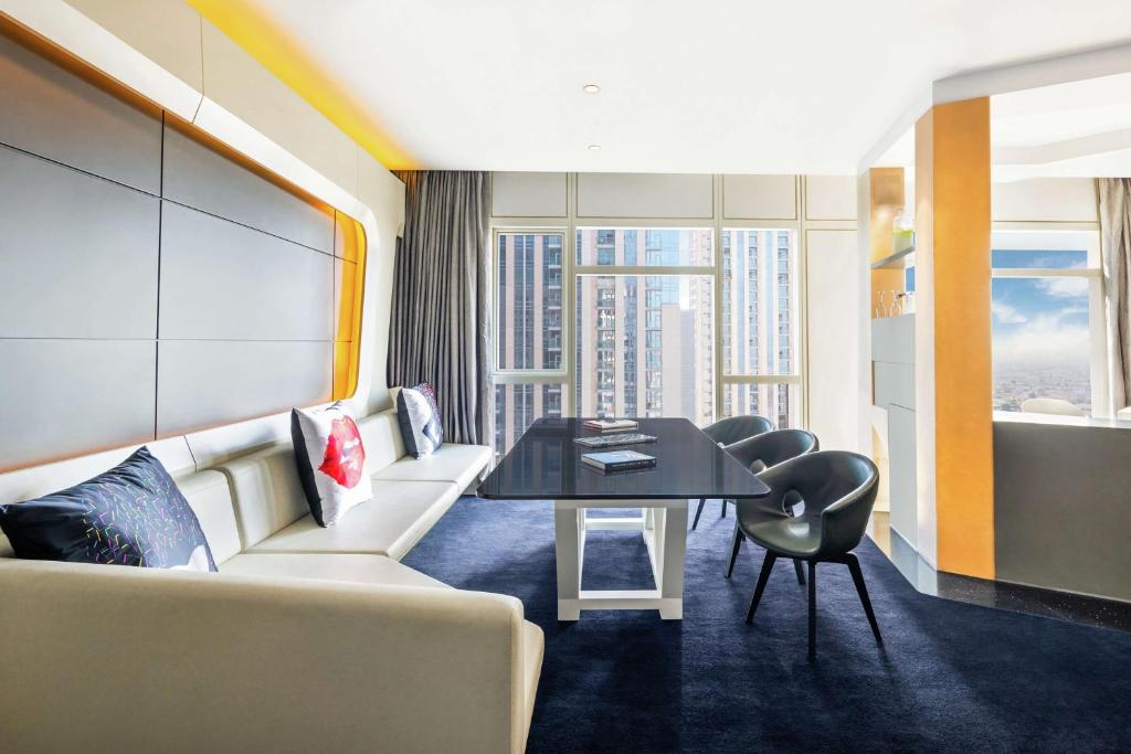 Mūsdienīgs viesnīcas numurs ar plašu dzīvojamo telpu, elegantu galdu un greznām mēbelēm. Lielie logi nodrošina dabiski apgaismotu atmosfēru un skatu uz pilsētu.