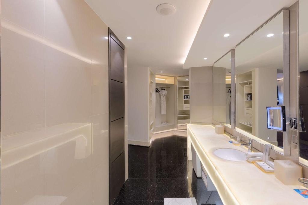 Mūsdienīgs un elegants vannas istabas interjers ar apgaismojumu, plašu spoguli un modernu aprīkojumu. Telpā ir arī drēbju skapis un vannas drēbes.