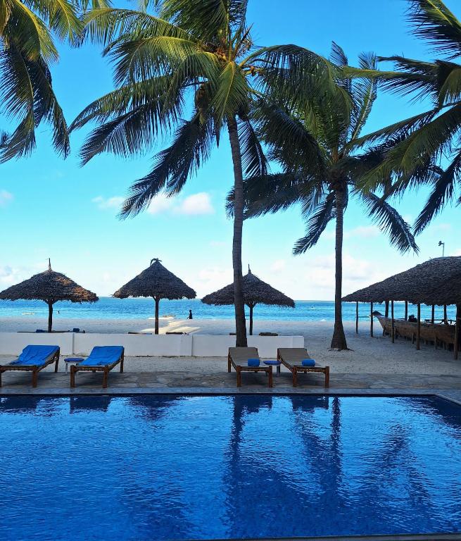 Baseins pie viesnīcas Bianco Azzuro ar palmām un pludmali fonā panoramic view with beach and pools