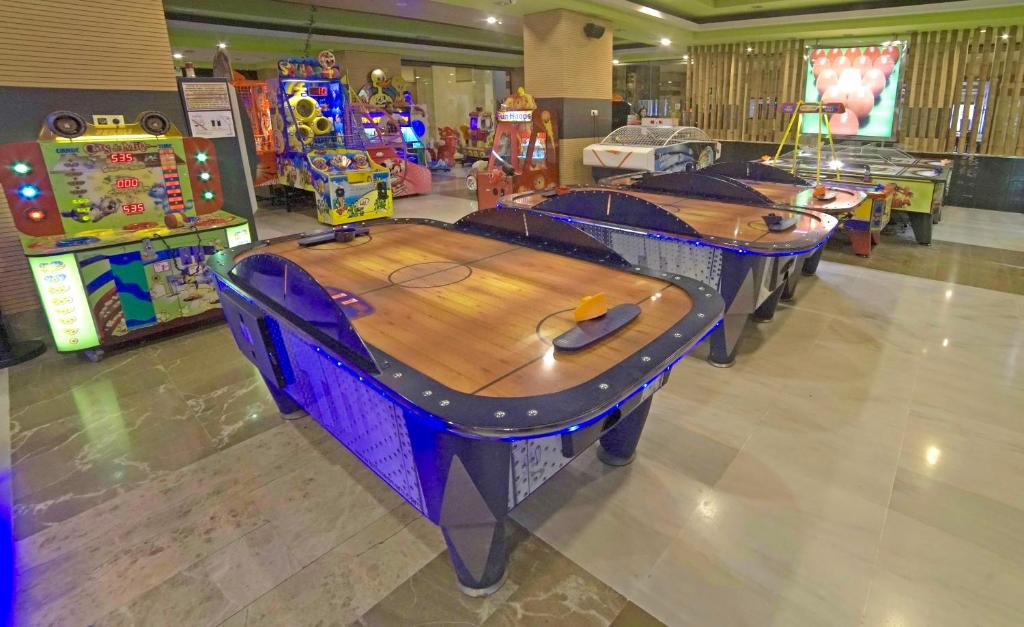 Aukstais gaisa hokeja galds arcade vidē ar dažādām spēļu mašīnām fonā, radot jautru un izklaidējošu atmosfēru.
