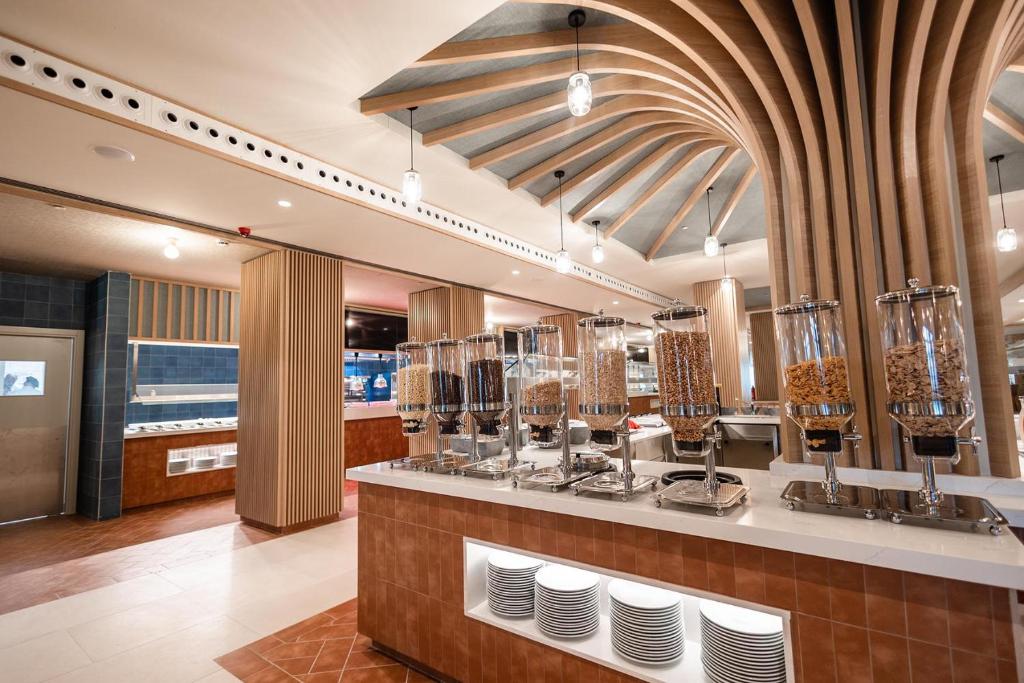 Mūsdienīgs restorāns ar elegantu interjeru, kurā ir redzami graudu dozatori un plaša bufete. Gaismas elementi un koka akcenti rada patīkamu atmosfēru.