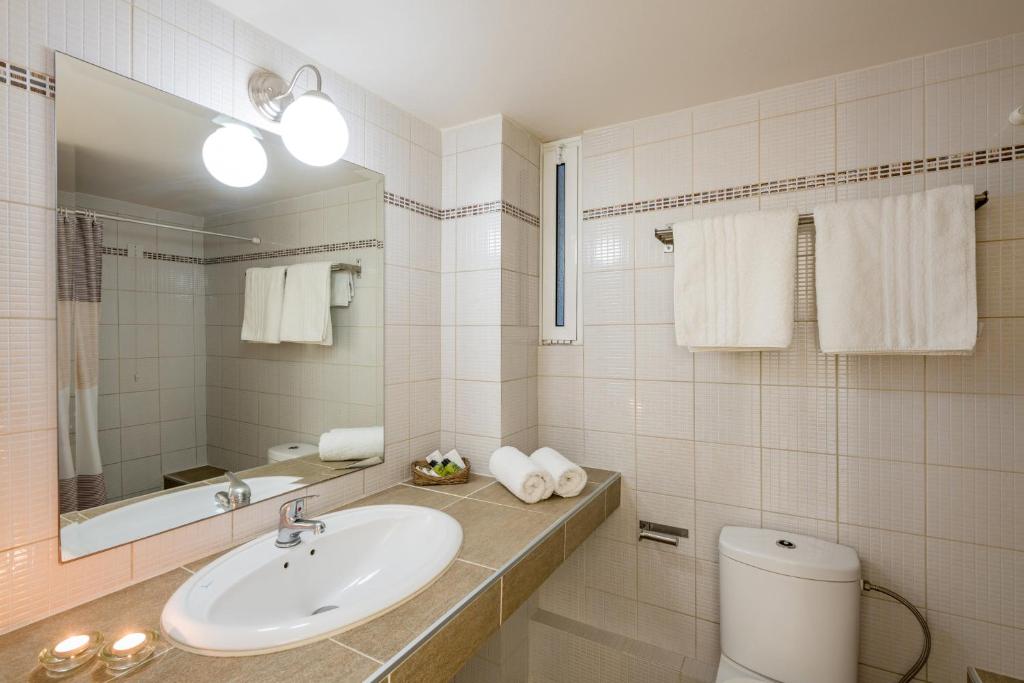 Mūsdienīga vannas istaba ar elegantiem akcentiem, tostarp izlietni, spoguli un dvieļiem. Telpa ir gaiša un sakopta, radot patīkamu atmosfēru.