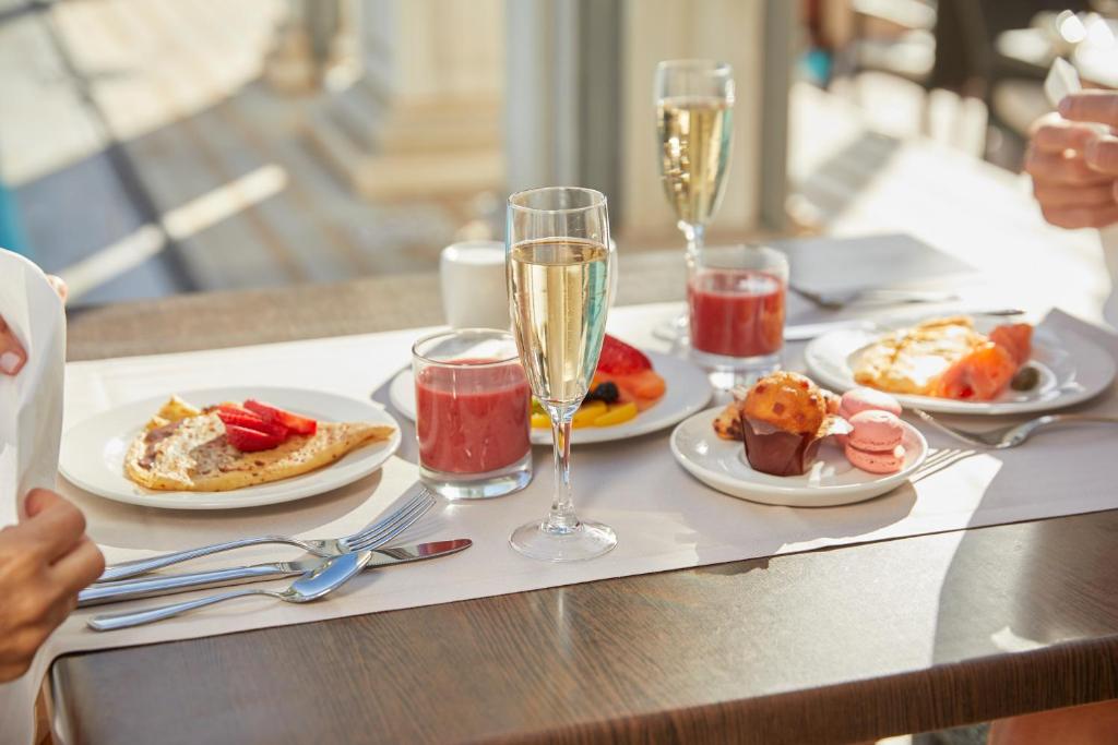 Broka ziemā ar šampanieti, augļiem, pankūkām un desertiem uz koka galda.