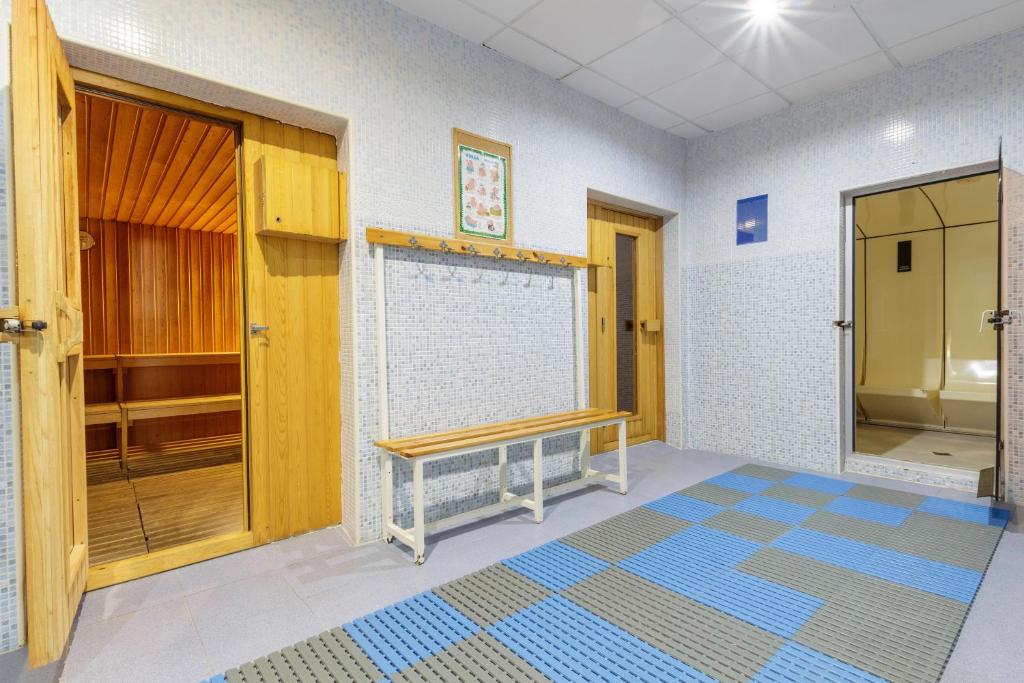 Sauna un dušas telpa ar koka mēbelēm un flīzētām sienām. Telpā ir uzkare un krēsls, kas nodrošina komfortu apmeklētājiem.