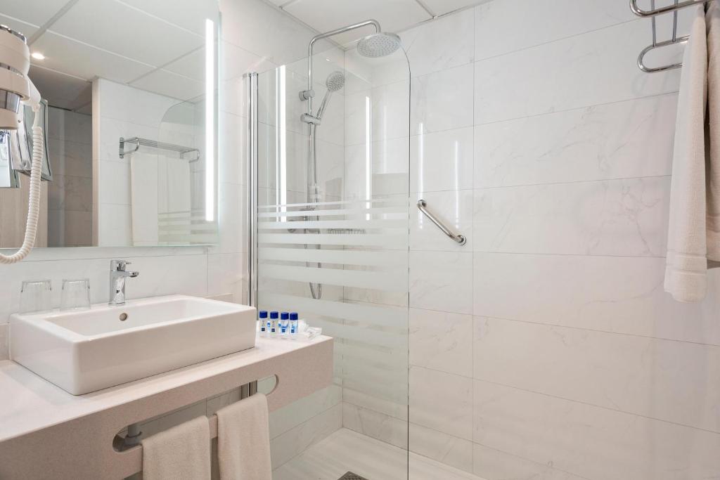Moderns vannas istabas interjers ar dušu, izlietni un higiēnas piederumiem, kas nodrošina komfortu un eleganci. Gaismas elementi piešķir telpai patīkamu atmosfēru.
