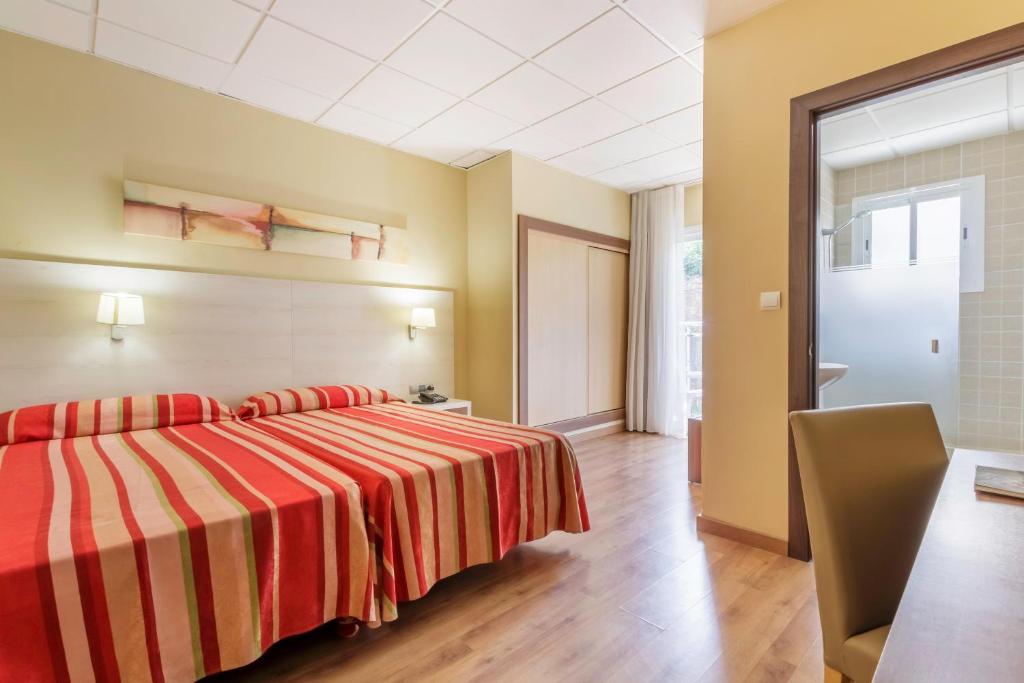 Mūsdienīgs viesnīcas numurs ar divām gultām, kas ierīkots ar sarkanu un baltu svītrainu gultas veļu. Telpā ir ērta mēbele, gaismas avoti un logs, kas nodrošina dabisko apgaismojumu.