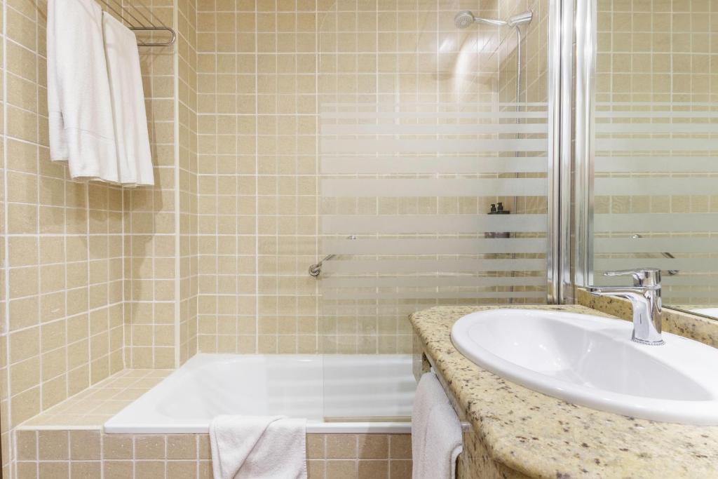 Moderns vannas istabas interjers ar dušu un vannu, akmens izlietni un flīzētu sienu. Svaigas dvieļi un higiēnas priekšmeti pieejami.