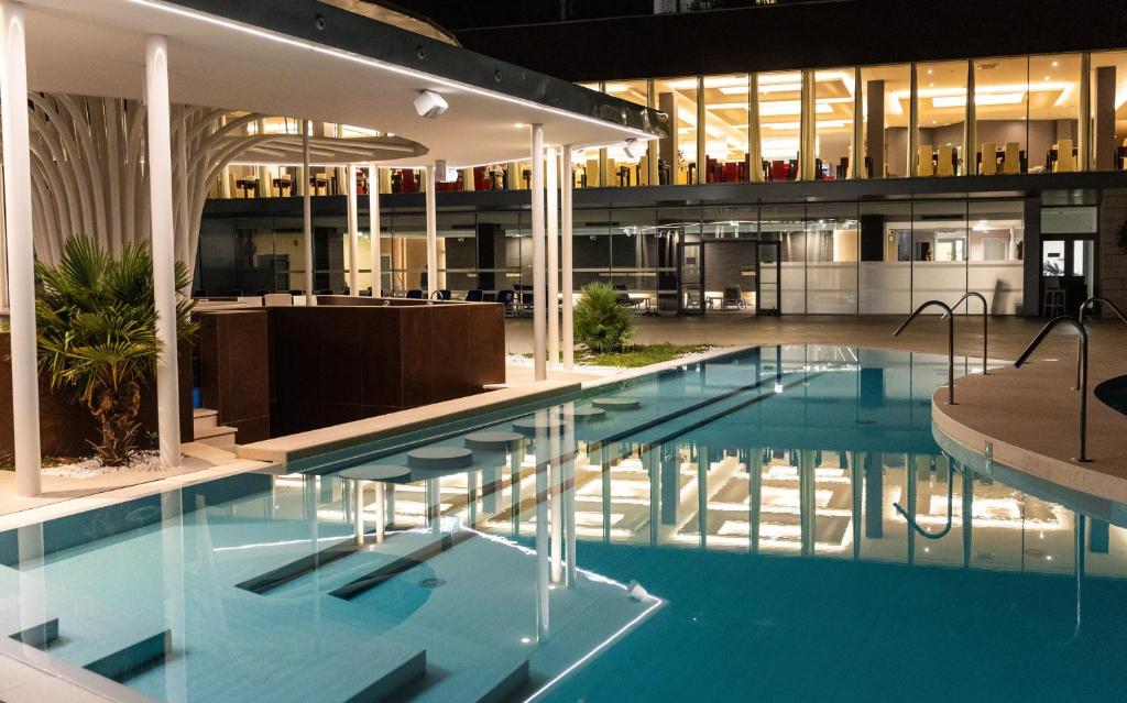 Mūsdienīgs peldbaseins ar gaismas atspulgiem, apkārtējā vide ir eleganta un stilīga, akcentējot mūsdienu arhitektūras elementus.