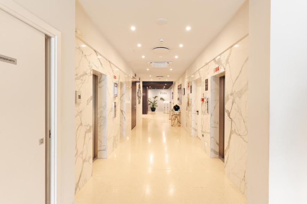 Mūsdienīgs koridors ar marmora sienām, liftu durvīm un mīkstu apgaismojumu, kas rada elegantu atmosfēru. Ievērojami elementi ir augi un gaumīgs mēbeļu dizains.