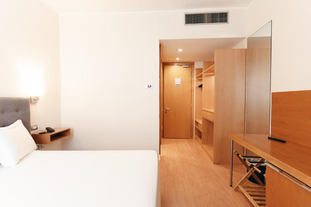 Mūsdienīga viesnīcas istaba ar vienkāršu interjeru, gultu, rakstāmgaldu un drēbju skapi. Telpa ir gaiša un plaša, ar modernām mēbelēm un siltu koka apdari.