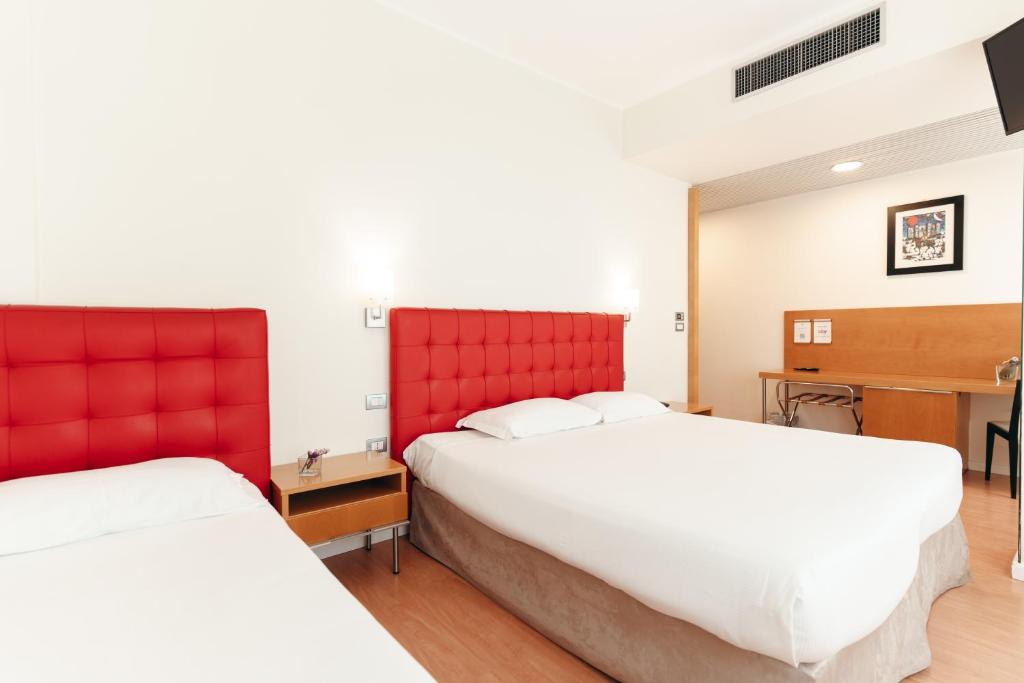 Sarkanu gultu istaba ar divām gultām, koka galdu un krēslu, mūsdienīgu dizainu un gaišām sienām. Ideāla telpa atpūtai un darbam.