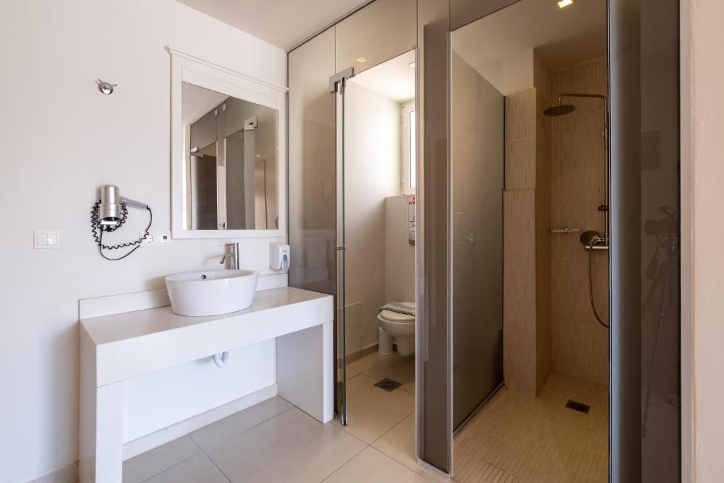 Mūsdienīgs vannas istabas interjers ar stikla dušu, modernu izlietni un spoguli. Vannas istaba apgaismota ar dabīgu gaismu caur logu.