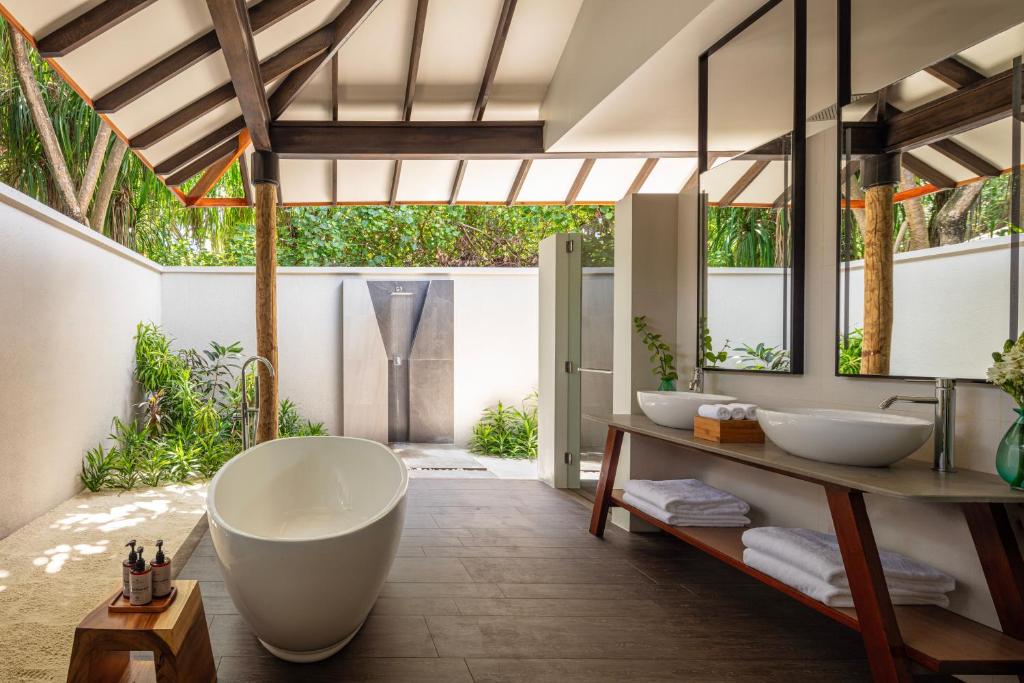 Mūsdienīgs un elegants vannas istabas interjers ar brīvdabas dušu, balto vannu un dabīgu apzaļumošanu. Gaismas un telpas harmonija rada relaksējošu atmosfēru.