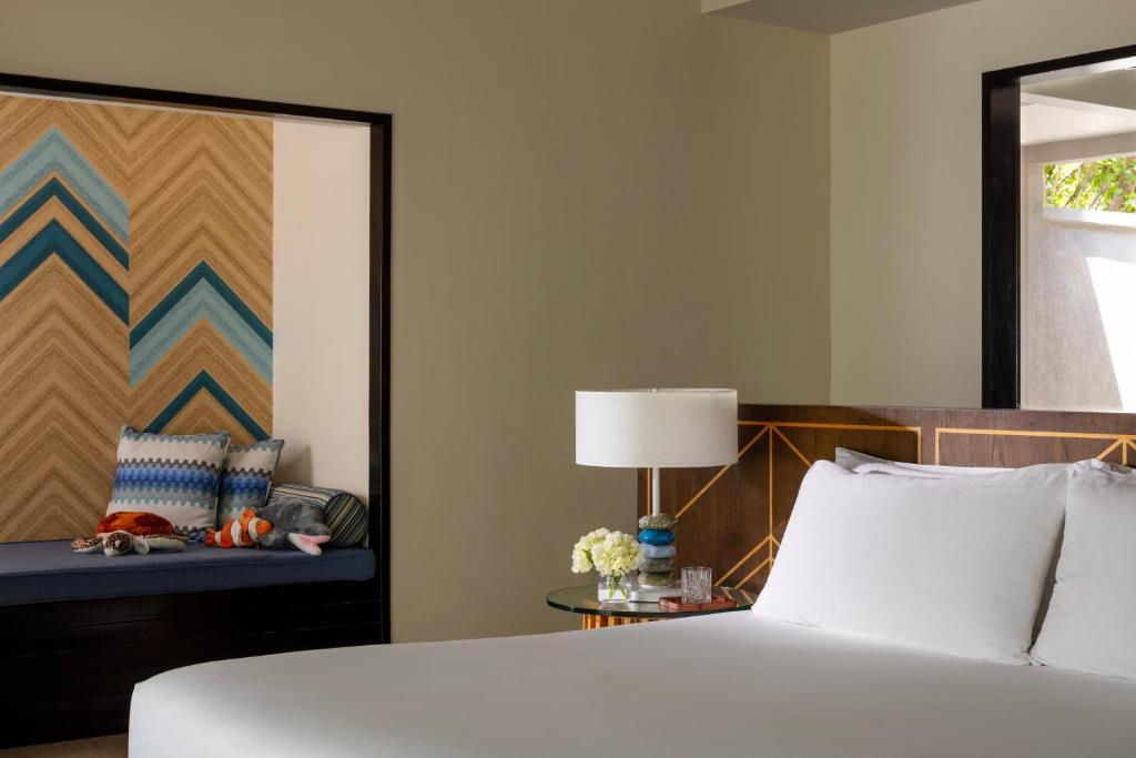 Moderns guļamistabas interjers ar spilgtiem akcentiem un ērtu atpūtas zonu. Sienas rotā ģeometriskais raksts, kas piešķir dzīvīgumu telpai.