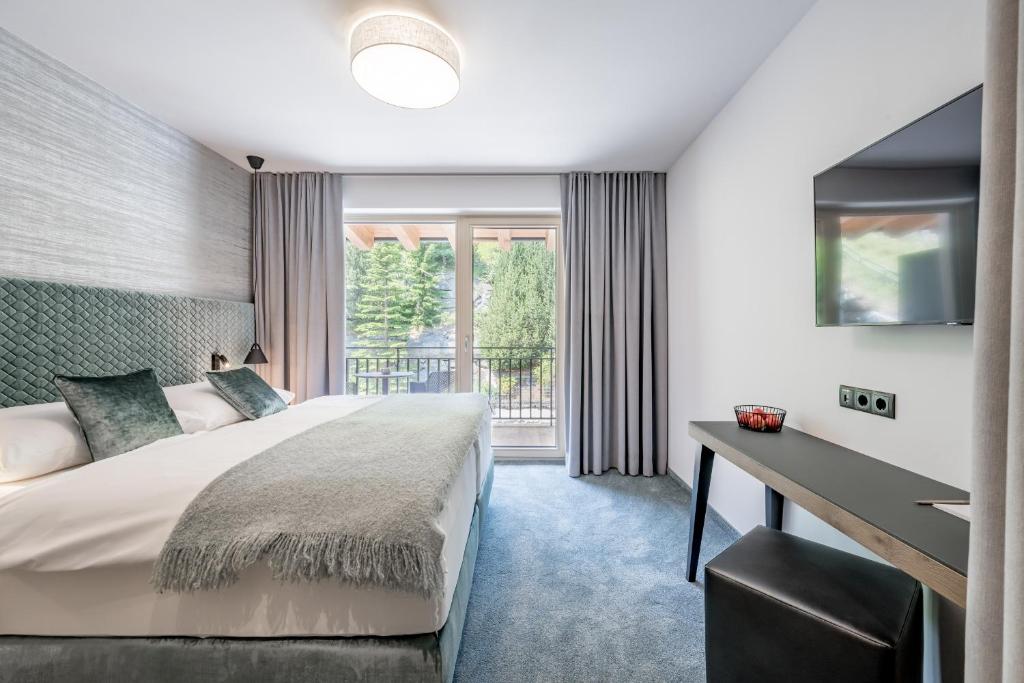 Mūsdienīgs guļamistabas interjers ar plašu gultu un skatu uz dabu caur lieliem logiem. Telpa ir iekārtota ar neitrālām krāsām un modernu mēbelēšanu, radot relaksējošu atmosfēru.