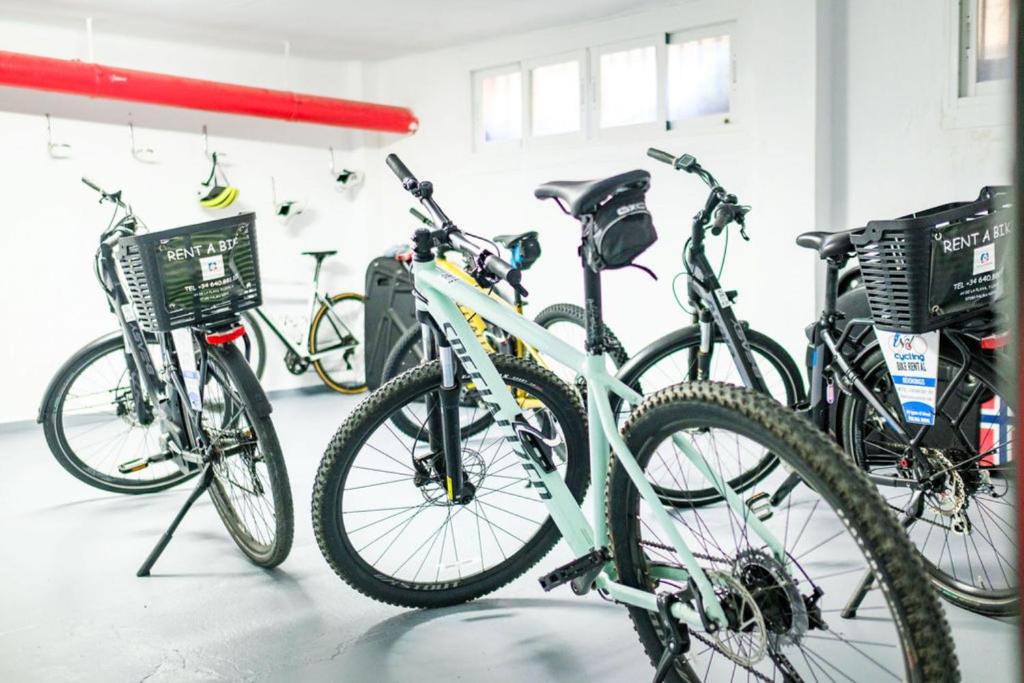 Velosipēdu noma ar dažādiem velosipēdiem, kas novietoti gaišā telpā. Izceļas moderns dizains un pieejamība.