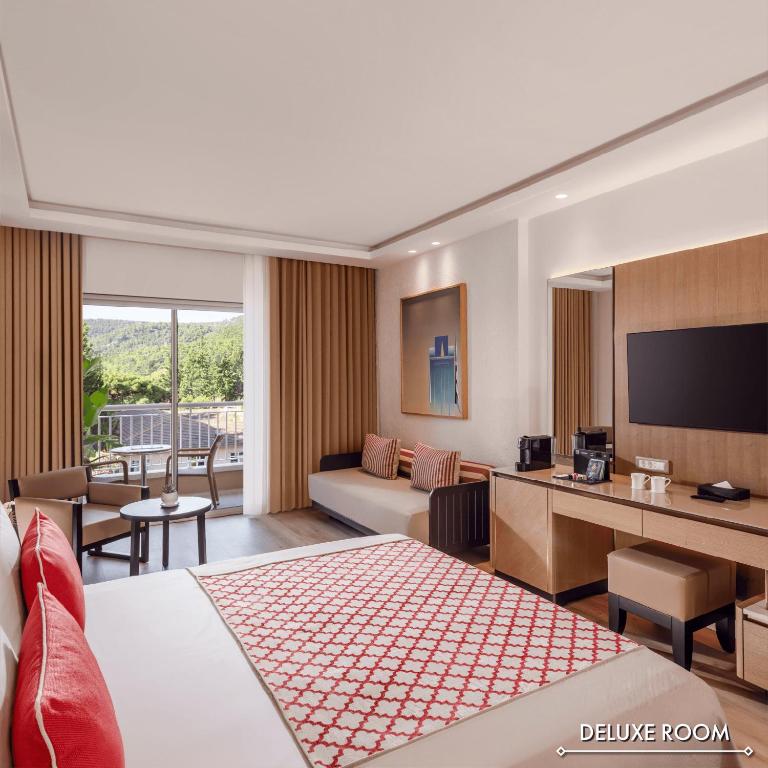 Mūsdienīga deluxe viesnīcas numura interjers ar skatu uz dabu, iekārtots ar ērtu mēbelēm un televizoru. Gaismas toni un stilīgi akcenti rada relaksējošu atmosfēru.