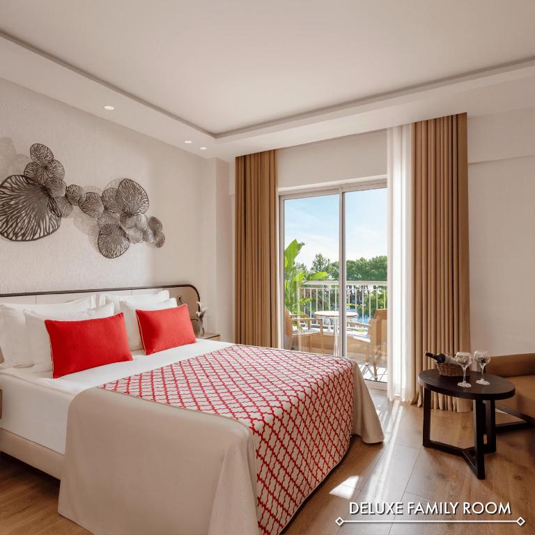 Mūsdienīgs un elegants ģimenes numurs ar divguļamo gultu, sarkaniem spilveniem un skatu uz baseinu. Telpa ir gaiša un plaša, ar dekoratīvām sienu detaļām un ērtu atpūtas zonu.