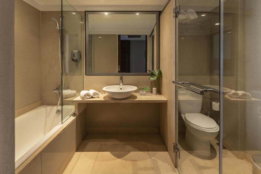 Mūsdienīgs vannas istabas interjers ar stikla dušu un bārdas vannu, kurā ir mūsdienīgas iekārtas un eleganta dizaina elementi.