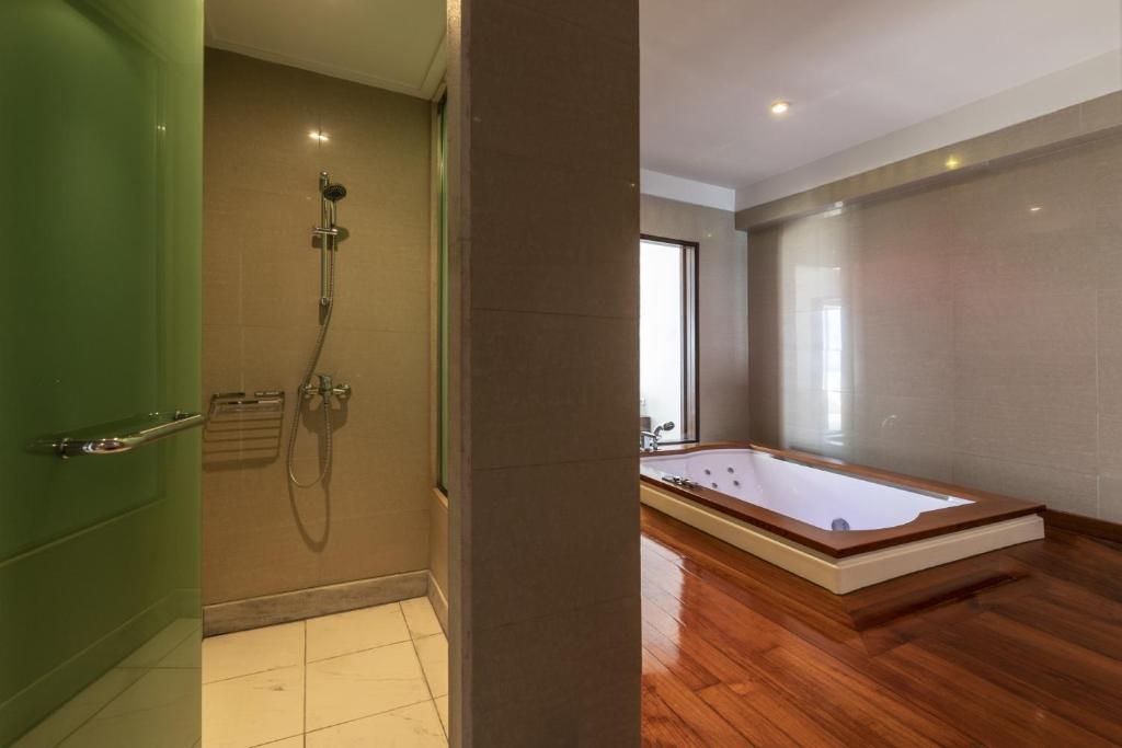 Mūsdienīga vannas istaba ar dušu un masāžas vannu, kurai ir koka apdare un lieli logi, kas nodrošina dabisko apgaismojumu.