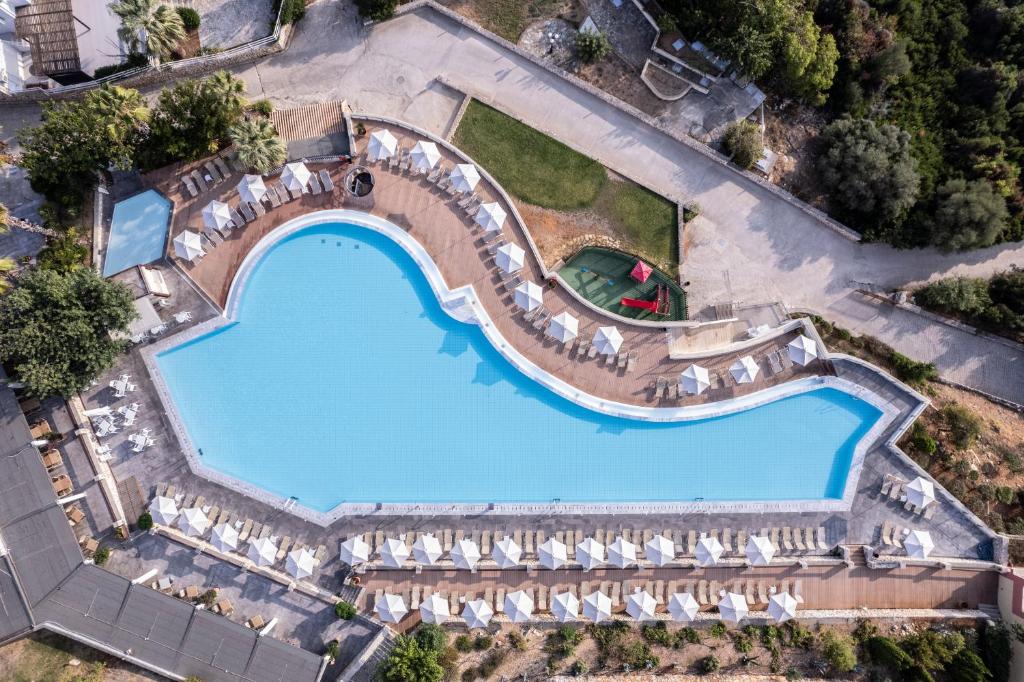 Aplūkojiet modernu baseinu ar unikālu formu, kas ieskauts saulessargu rindās un apkārtējiem zaļumiem. Ideāla vieta relaksācijai un atpūtai.