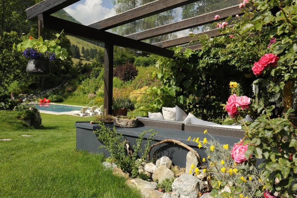 Skaista dārza ainava ar peldbaseinu, ziediem un atpūtas zonu zem koka konstrukcijas. Ideāla vieta relaksācijai un atpūtai dabā.