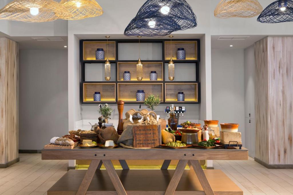 Elegants bufetes galds ar dažādiem ēdieniem un dzērieniem, izsmalcināti interjera elementi un mūsdienīga apgaismojuma kompozīcija.