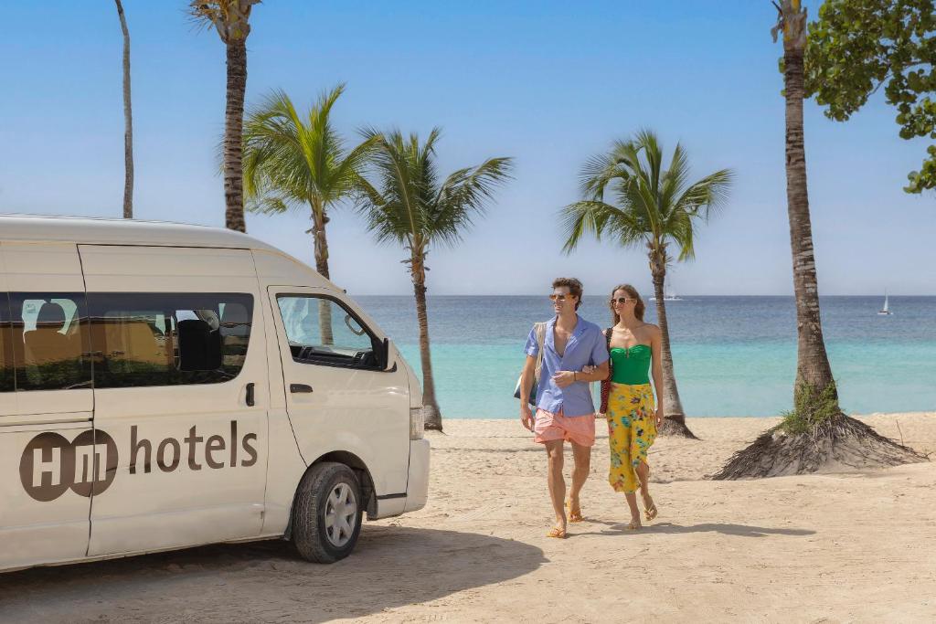 Pāris pastaigā gar pludmali, blakus HM hotels autobusiņam, ar palmām un skaistu jūras skatu fona.