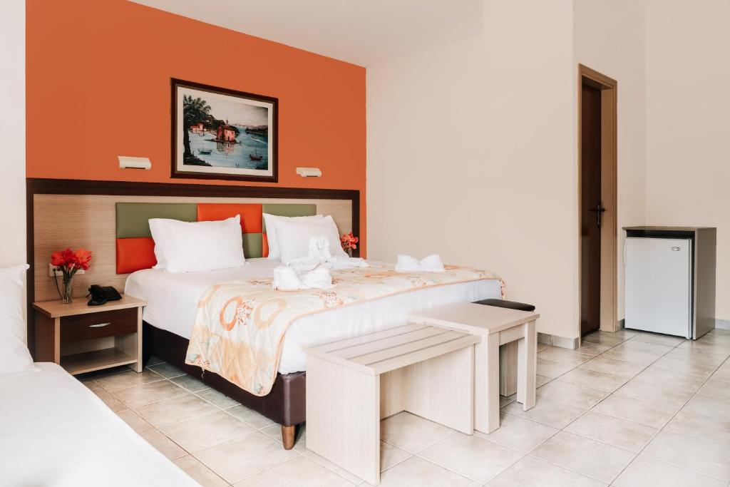 Mūsdienīga viesnīcas numura iekārtojums ar divguļamo gultu, elegantu deko un maziem mēbeļu elementiem. Siltas krāsas un mākslinieciska bilde rada patīkamu atmosfēru.