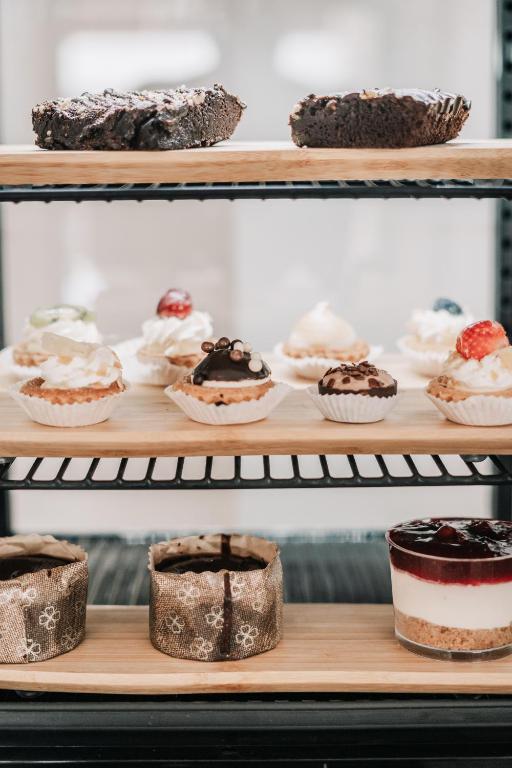 Konditorejas izstrādājumi uz trīs plauktiem, tostarp šokolādes kūka, mazi kēksi ar krēmu un ogām, kā arī biskvīta deserts ar ogu mērci.