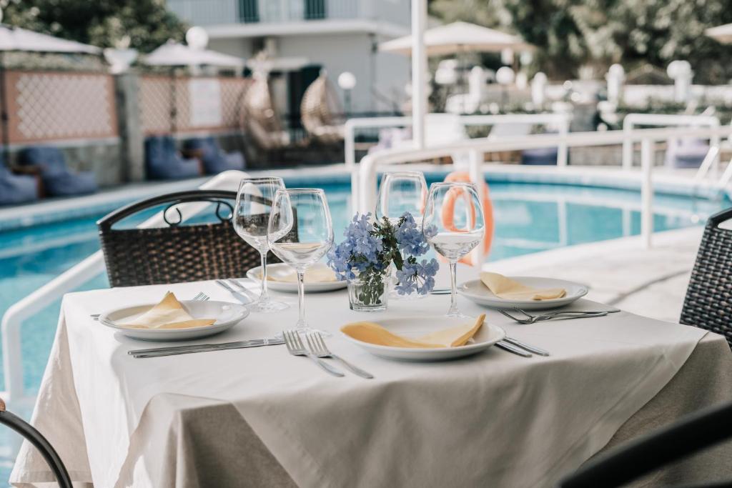 Elegants galdiņš ar ziediem un galda piederumiem pie baseina, radot patīkamu un relaksējošu atmosfēru. Ideāls skats romantiskām vakariņām vai svinībām.