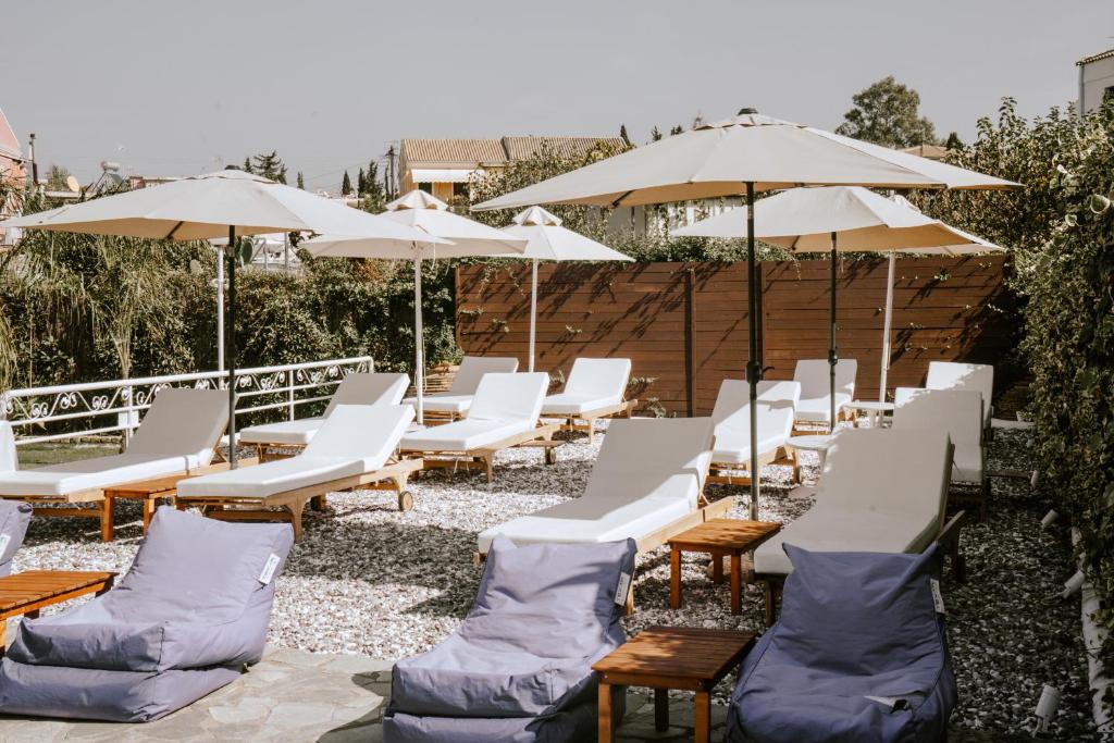 Sauļošanās krēsli un saulessargi dārzā, ideāla vieta relaksācijai un atpūtai. Apvidus ir klāts ar oļiem, radot mierīgu un patīkamu atmosfēru.