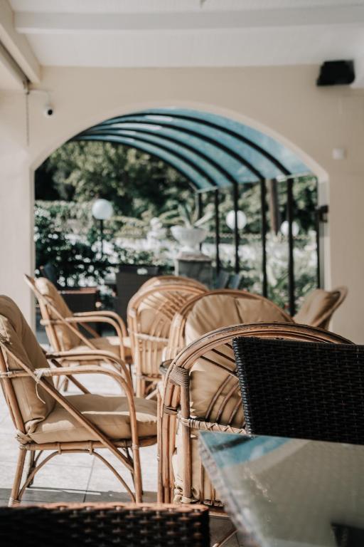 Rūpīgi iekārtota terase ar rattan krēsliem un skatu uz dārzu, radot mierīgu un relaksējošu atmosfēru.