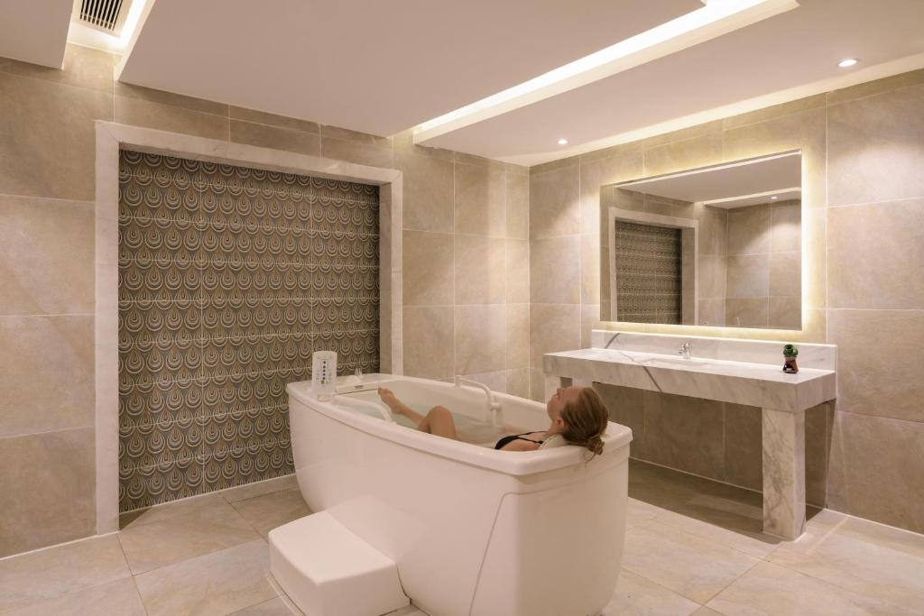 Mūsdienīga vannas istaba ar elegantu vannu un stilīgu spoguli, radot relaksējošu atmosfēru. Sienas ir apšūtas ar modernu flīžu dizainu, kas piešķir telpai unikālu raksturu.