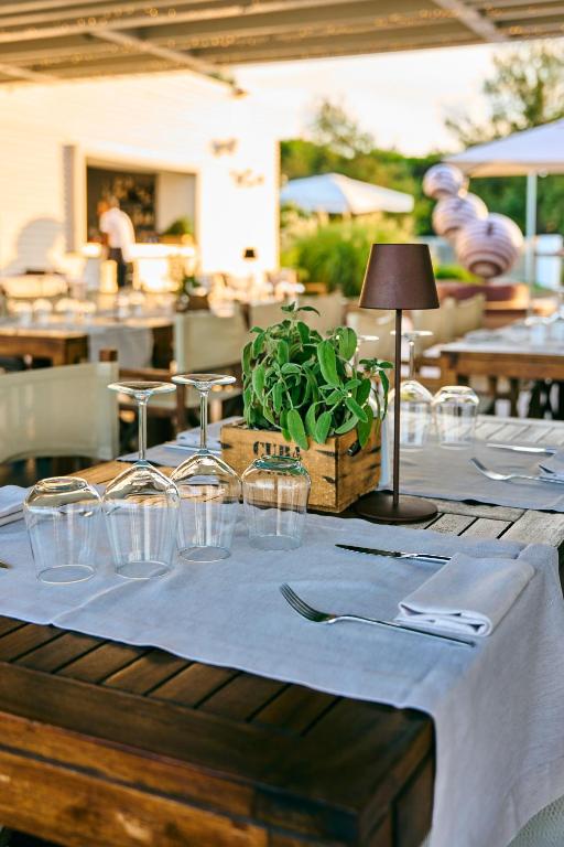 Elegants restorāna galds ar glāzēm, dekoratīvu lampu un zaļiem augiem, kas radīts relaksētai atmosfērai. Ideāli piemērots maltītēm ārā.