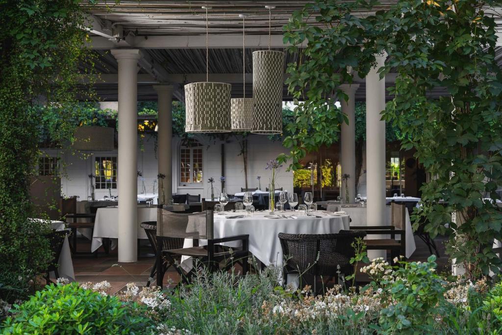 Elegants restorāns ar galdiem un izsmalcinātu apgaismojumu, ieskauts zaļumos un ziedos. Ideāla vieta romantiskām vakariņām vai svinībām.