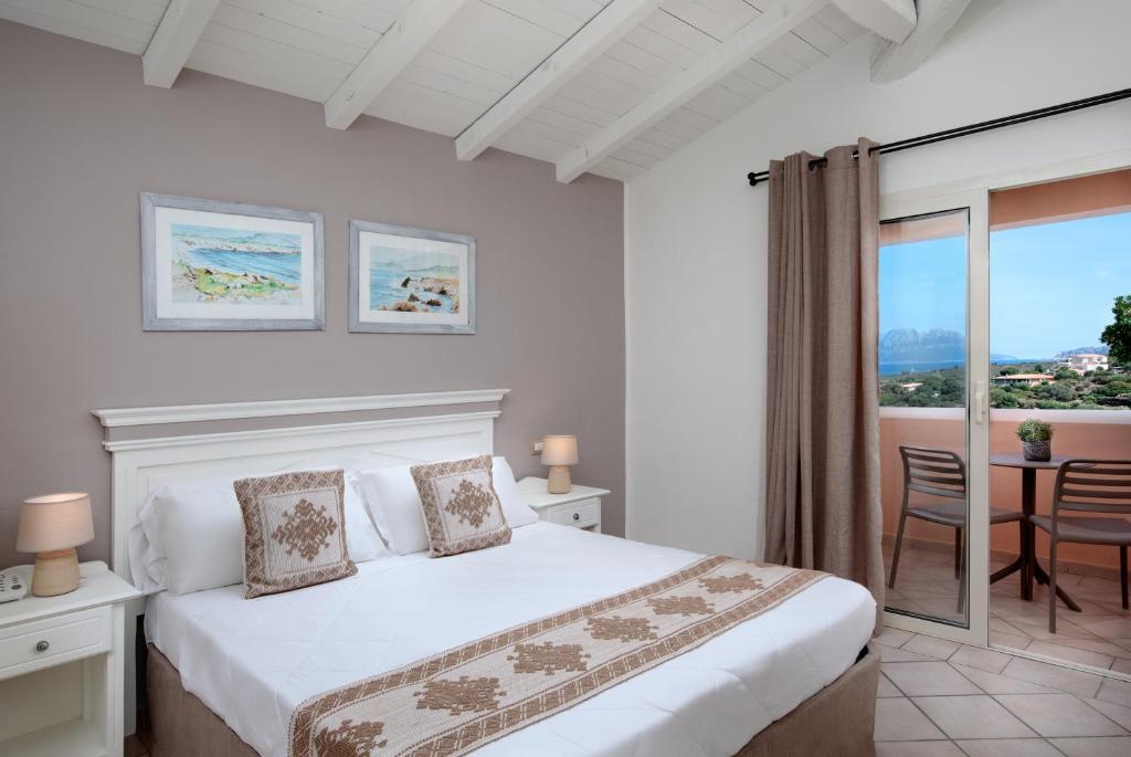 Mūsdienīga guļamistaba ar ērtu divguļamo gultu, dekoratīvām spilveniem un gleznām uz sienām, kas piedāvā skatu uz dabu caur balkonu.