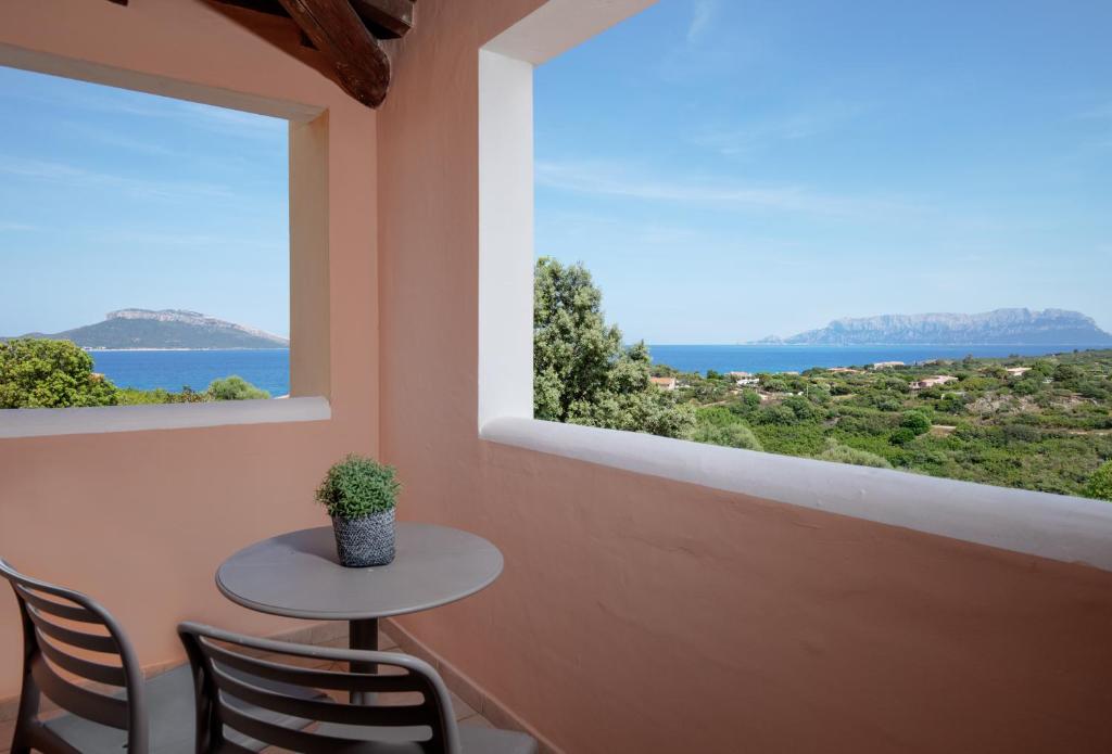 Skats no balkona uz jūru un kalniem, ar galdu un krēsliem, kas papildina relaksējošo atmosfēru. Daba un mierīga vide rada ideālu vietu atpūtai.
