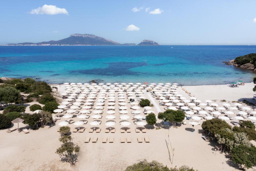 Skaists pludmales skats ar baltām saulessargiem un saulē iemirdzošiem smiltīm, kurā redzama dzidra zila jūra un tuvumā esošas salas. Ideāla vieta atpūtai un relaksācijai pie jūras.