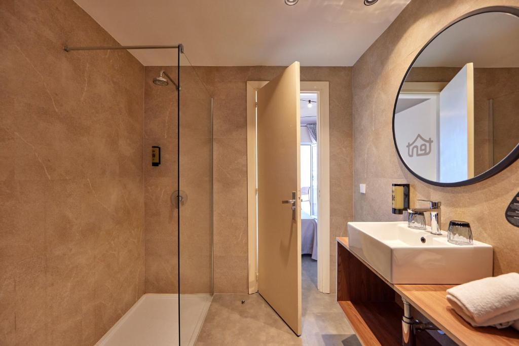 Mūsdienīgs vannas istabas interjers ar dušas kabīni, izlietni un spoguli, radot elegantu un funkcionālu atmosfēru.