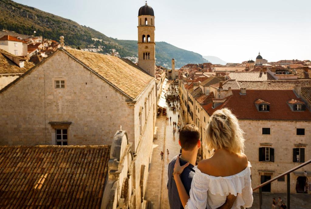 Pārsteidzoša skats uz Dubrovniku ar pāri, kas baudīšanu brīdi, skatoties uz pilsētas ielām un vēsturiskām ēkām.