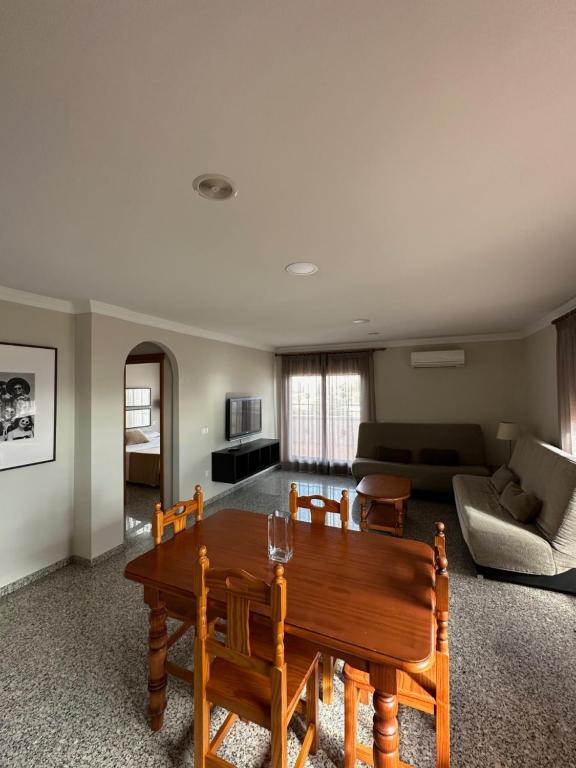 Mūsdienīga viesistaba ar ēdamgaldu, dīvānu un televizoru. Telpa ir gaiša ar logiem, kas ļauj ieplūst dabīgajai gaismai.