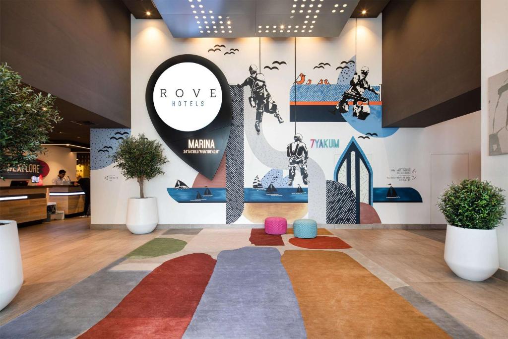 Rove Dubai Marina viesnīcas recepcija ar māksliniecisku sienas dizainu.
