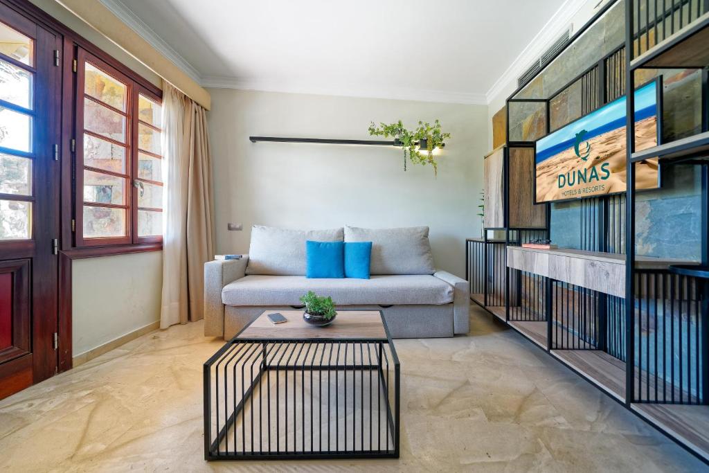 Mūsdienīgs viesnīcas numurs ar ērtu dīvānu, stilīgu galdu un televizoru, kas izceļ viesnīcas zīmolu "Dunas". Gaisīgs interjers ar dabīgiem materiāliem un logiem, caur kuriem ieplūst dienas gaisma.