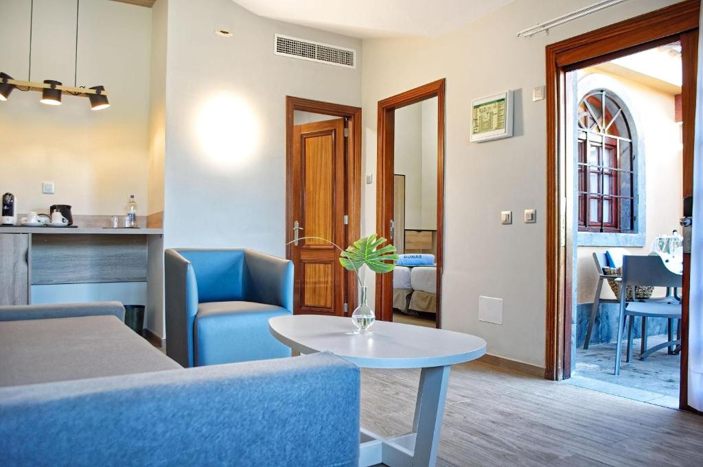 Mūsdienīga viesnīcas istaba ar ērtu dīvānu, kafijas staciju un atvērtu durvju pieeju uz āra terasi. Interjers ir gaišs un elegants, radot patīkamu atmosfēru.