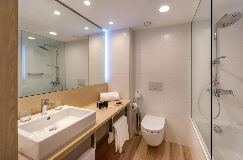 Moderns vannas istabas interjers ar koka akcentiem, augstas kvalitātes santehniku un higiēnas produktiem. Telpa ir gaiša un eleganta, nodrošinot komfortu un stilu.