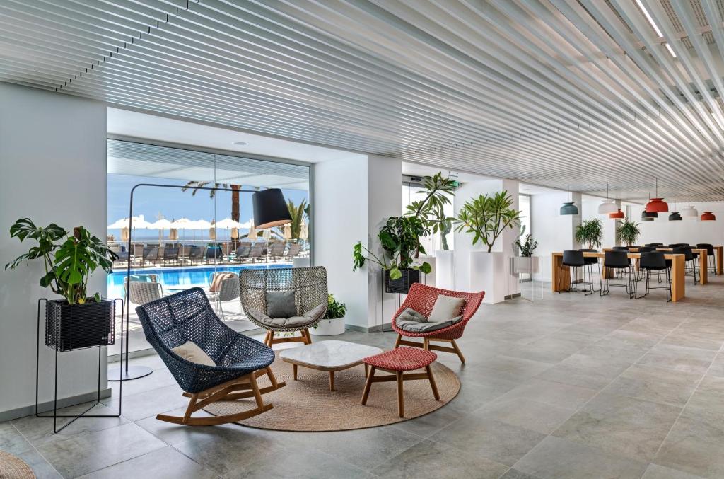 Mūsdienīgs interjers ar komfortablām atpūtas krēslām un daudzām augiem, kas rada patīkamu atmosfēru. Skats uz peldbaseinu un terasi, kas papildina telpas estētiku.