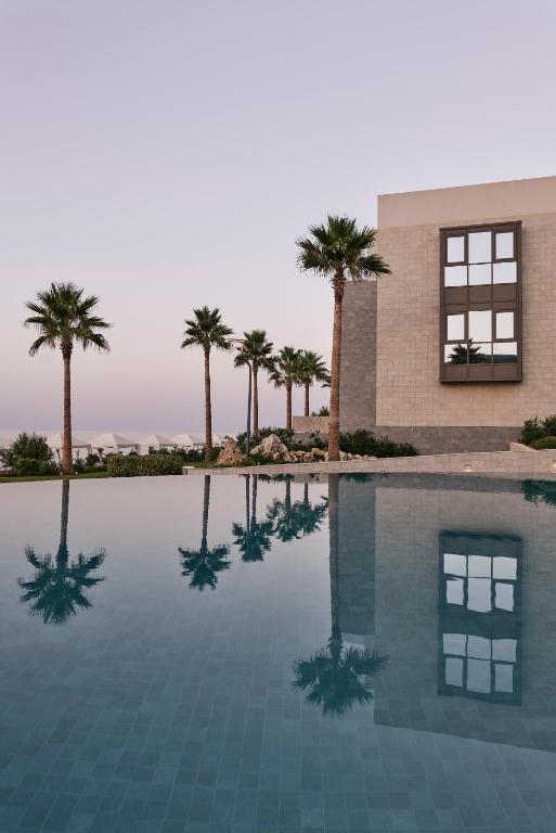Mūsdienīgas villas ar palmu ainavu un atspulgām baseinā, kas rada mierīgu atmosfēru.