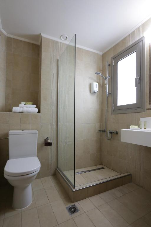 Mūsdienīgs vannas istabas interjers ar dušu, tualeti un izlietni, kas izstrādāts neitrālās krāsās. Vannas istabā ir liels logs, kas nodrošina dabīgu apgaismojumu.