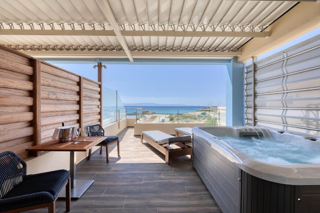 Mūsdienīgs balkons ar burbuļvannu un skatu uz jūru, iekārtots ar koka sienu, ērtām krēsliem un galdu. Ideāla vieta relaksācijai un atpūtai.